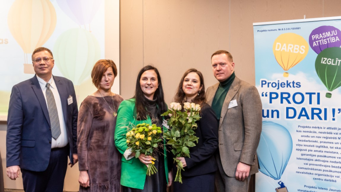 Projekta “Proti un Dari” noslēguma pasākuma dalībnieki pie plakāta 30.11.2023.