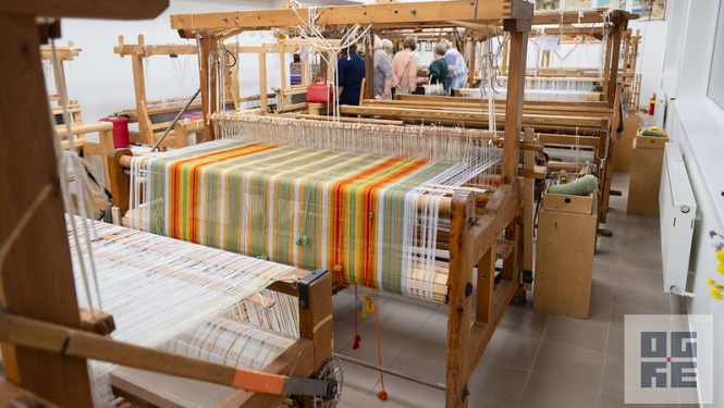 Stelles ar daļēji uzaustu krāsainu lakatu, aiz tām cilvēki, kas piedalās Radošās telpas atklāšanā