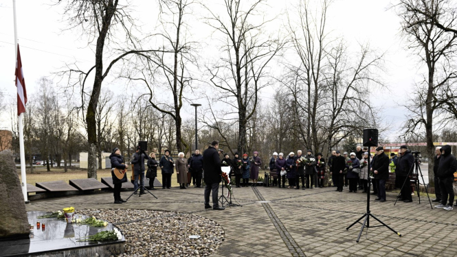 Ogres novada pašvaldības domes priekšsēdētājs Egils Helmanis un citi cilvēki stāv pie represēto piemiņas akmens Ogrē