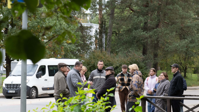 RTU profesori, studenti, Egils Helmanis stāv un sarunājas ielas malā, fonā balts mikroautobuss 09.10.2024.