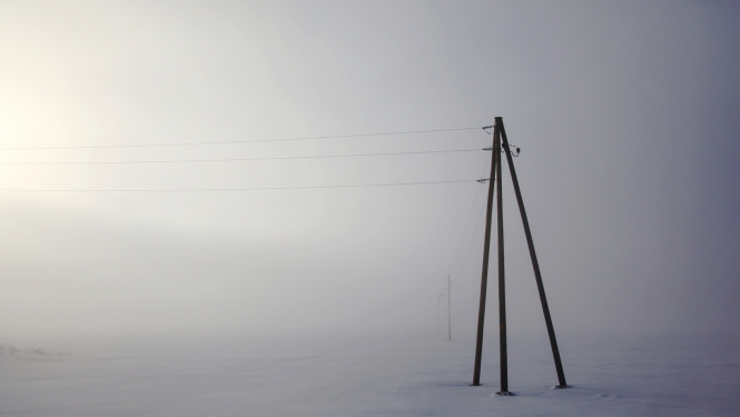 Elektrības stabi ar vadiem sniegotā laukā