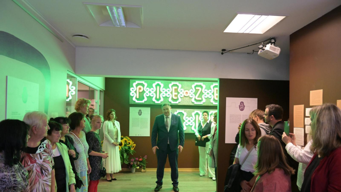 Egils Helmanis, fona uzraksts pie Zelta liepas, gar malu stāv cilvēki 23.08.2024.