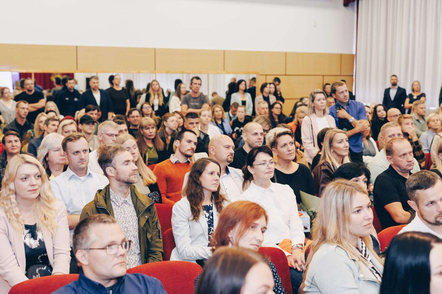 Ķeguma pamatskolā atklāta “zaļā klase” – jauna āra telpa skolēniem un kopienai. Vecāki zālē uzklausa prezentāciju