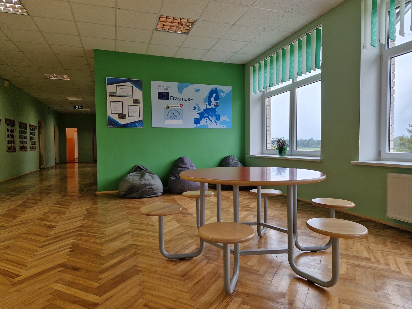 Skolas vestibils ar apļveida galdu un soliem un programmai Erasmus+ veltītām planšetēm