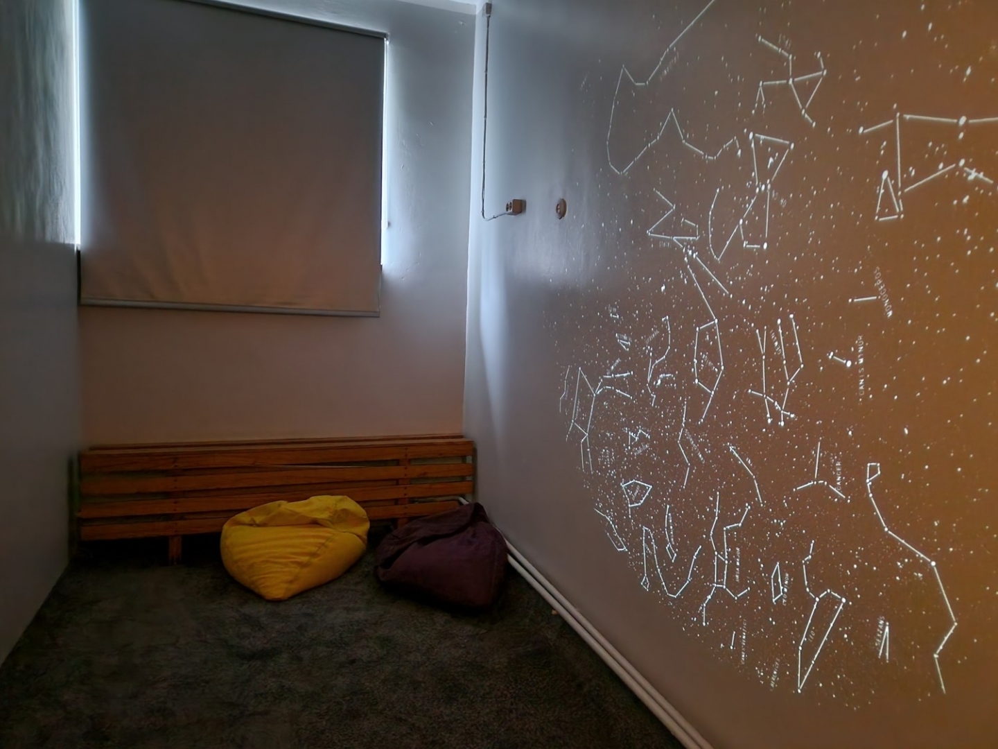 Astronomijas kabinets ar diviem pufiem un izgaismotiem zvaigznājiem uz sienas