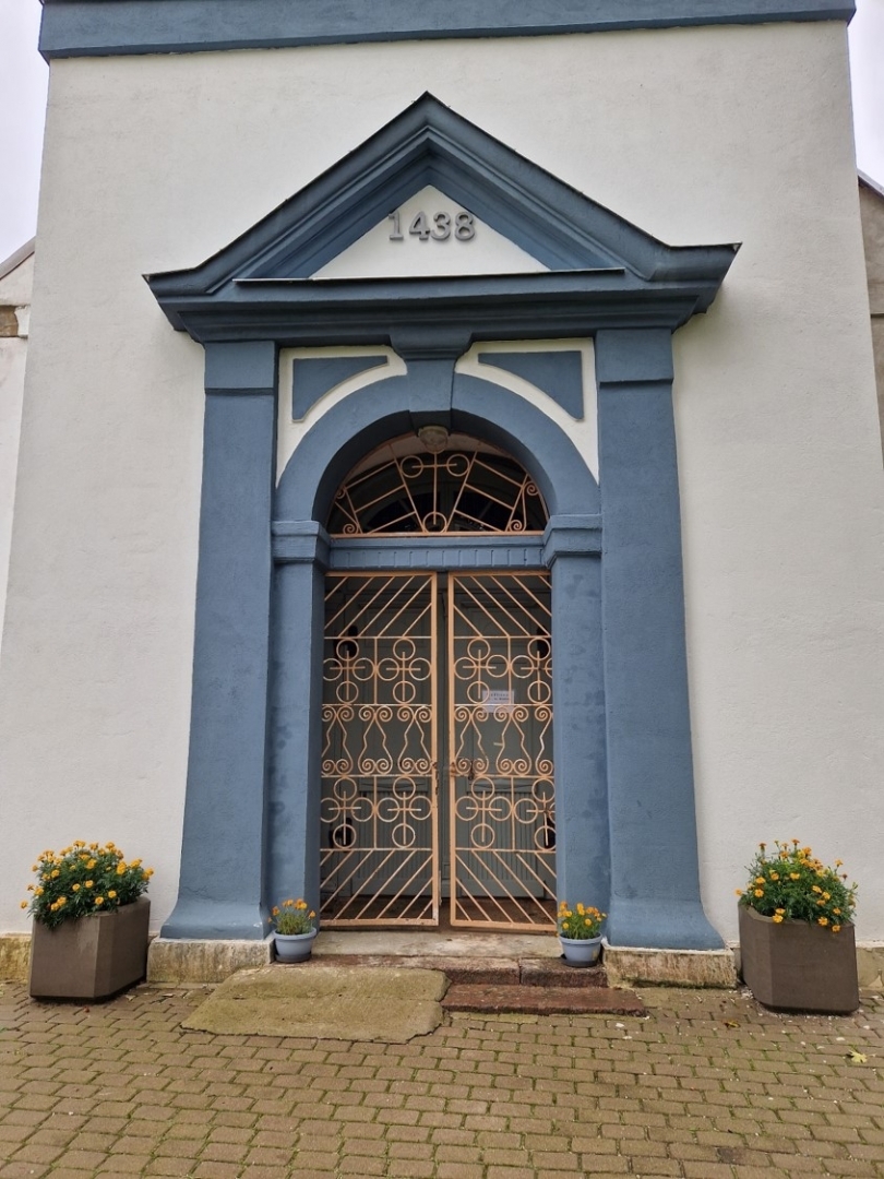 Baznīcas galvenās ieejas durvis ar dekoratīviem puķu podiem