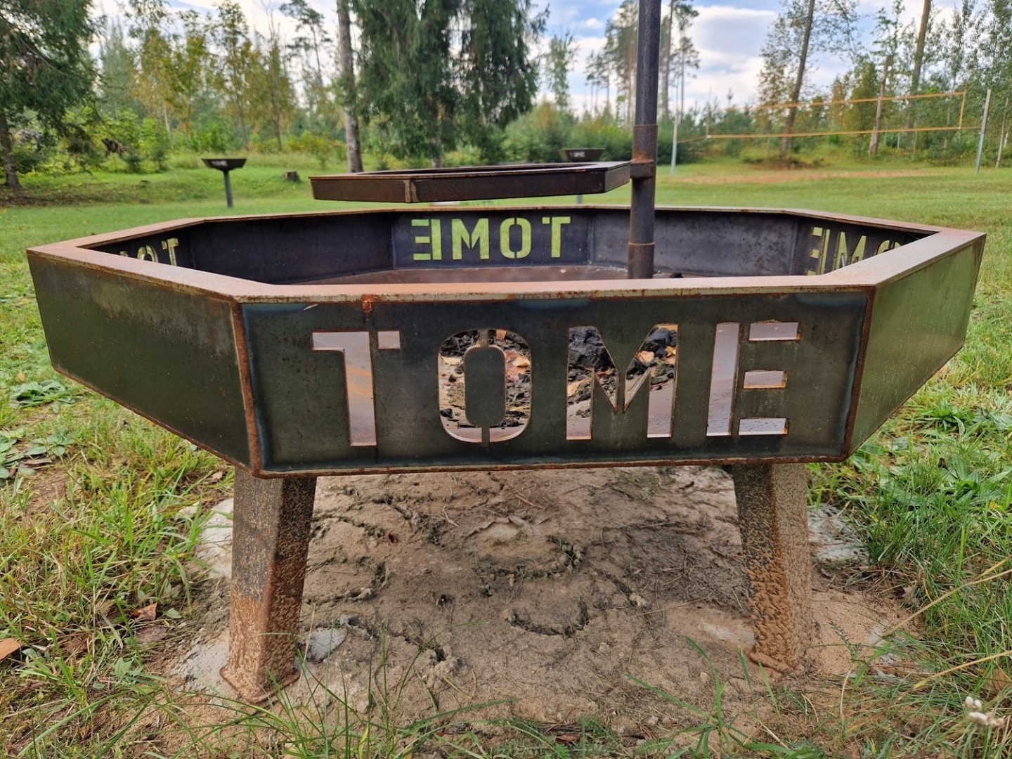 Metāla ugunskura vietas pamatne ar uzrakstu "Tome"