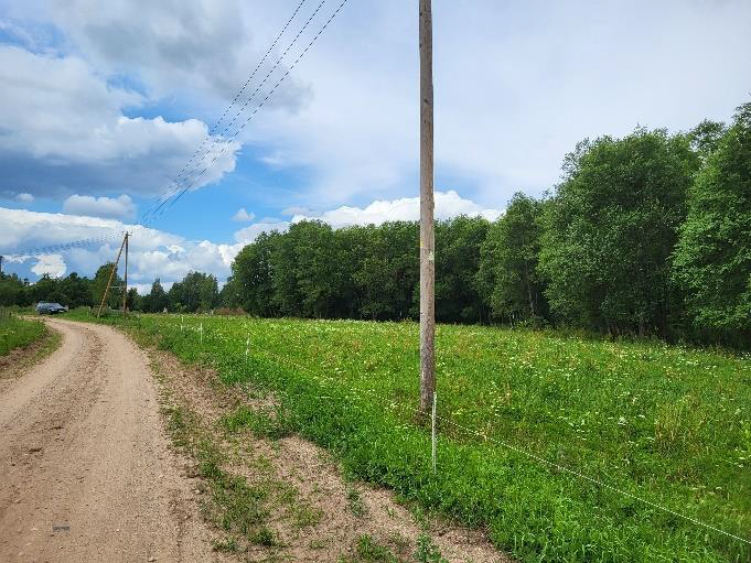 Zemes gabals - pļava ar ceļu un elektrības stabiem