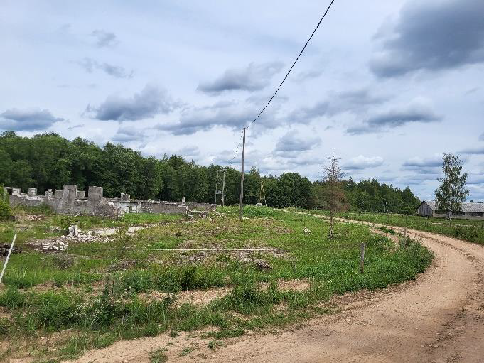 Zemes gabals - pļava ar ceļu, elektrības stabiem un mūra paliekām