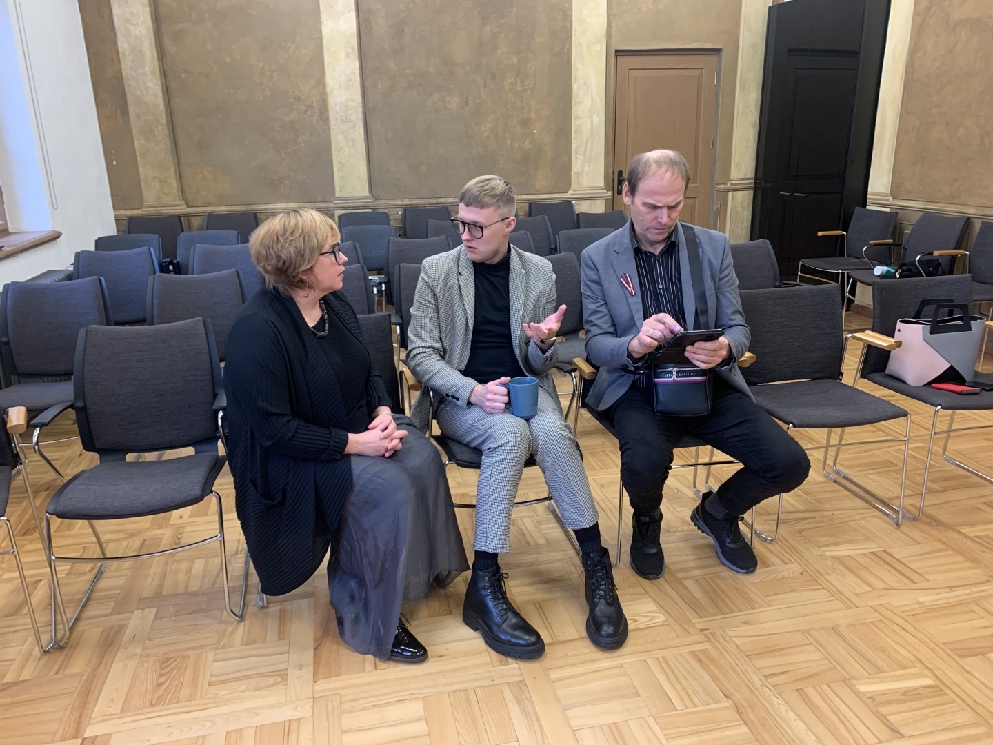 Divi būvvaldes pārstāvji un Ķeipenes pārvaldes vadītājs sēž pasākuma norises zālē