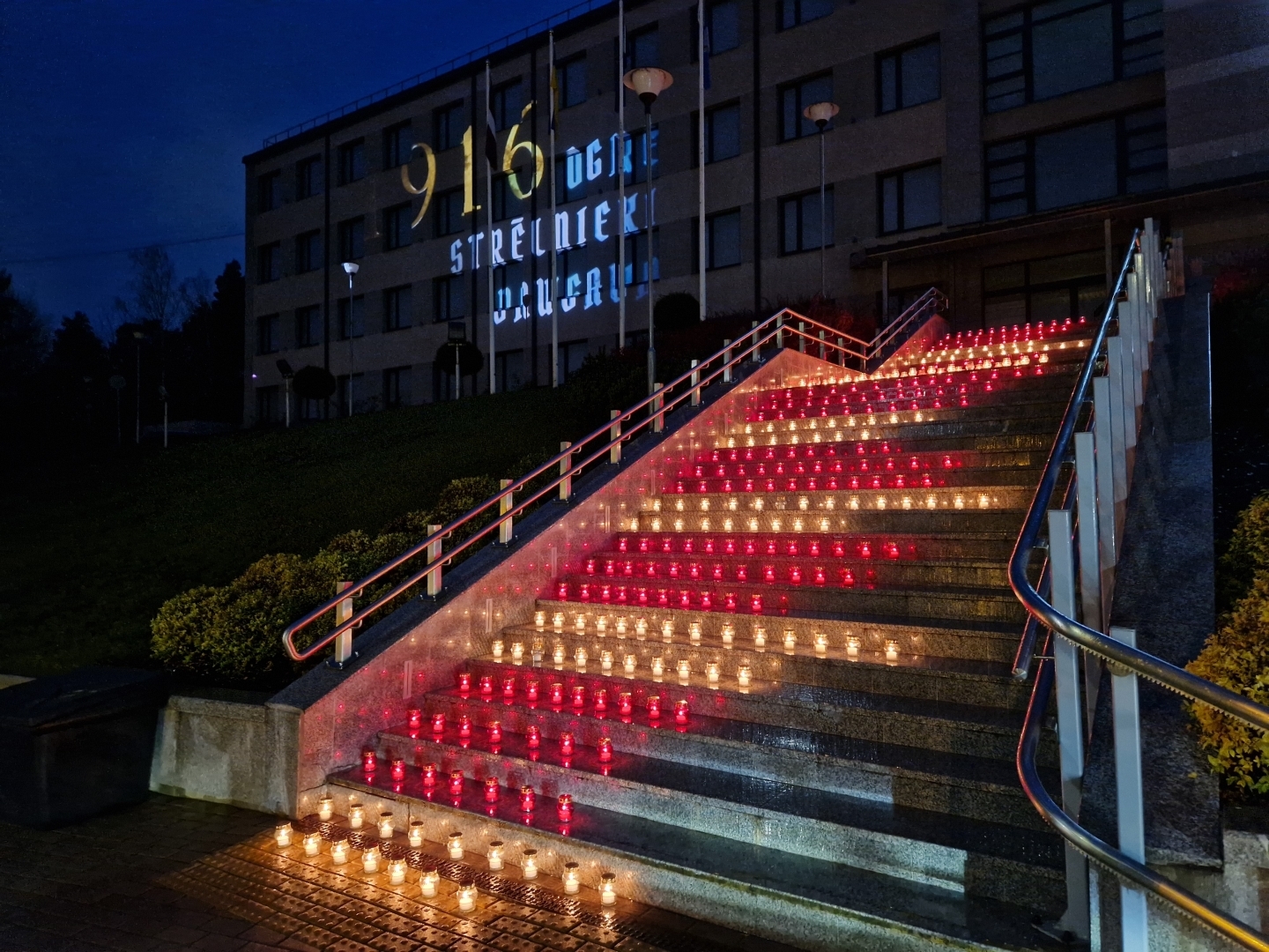Sarkanbaltsarkanas svecītes uz pašvaldības ēkas kāpnēm un filmas demonstrācija uz ēkas sienas