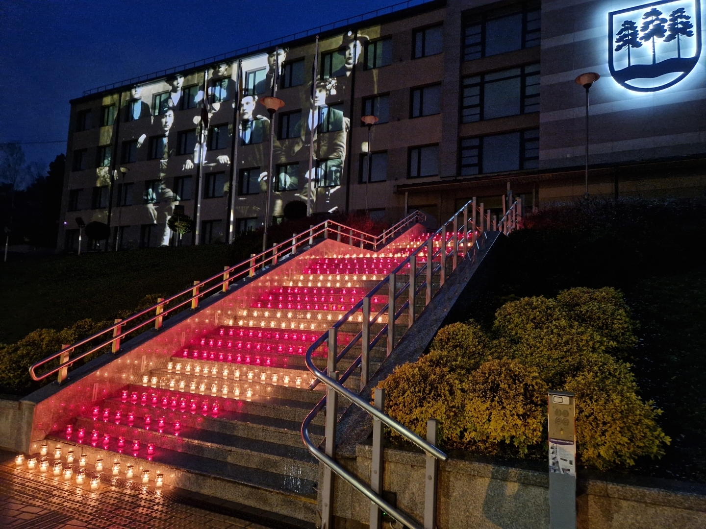 Sarkanbaltsarkanas svecītes uz pašvaldības ēkas kāpnēm un filmas demonstrācija uz ēkas sienas