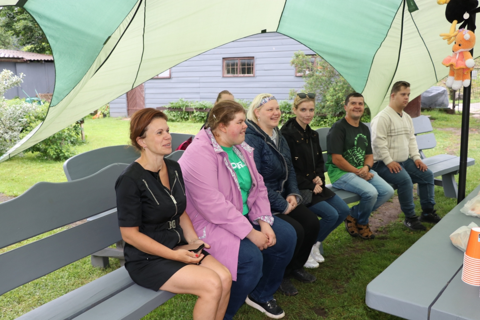 Sociāla uzņēmēja pie Zelta liepas darbinieki sēž uz soliņa 19.06.2024.