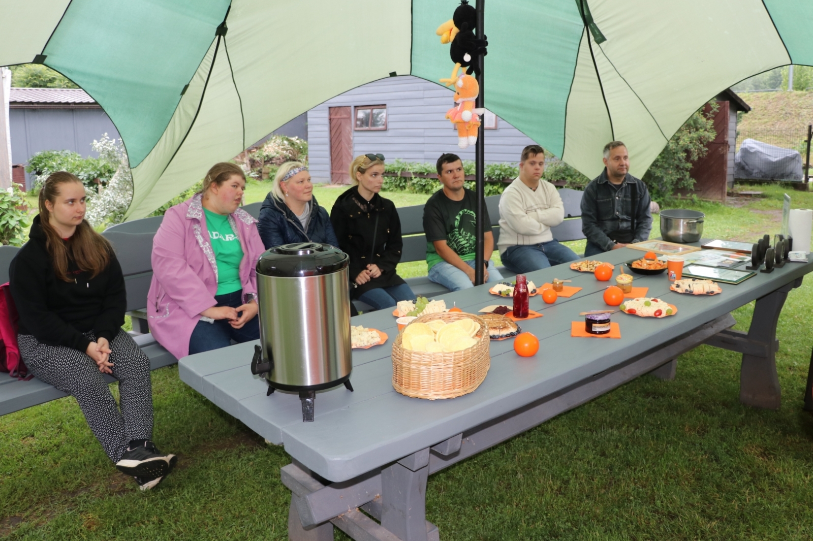 Sociāla uzņēmēja pie Zelta liepas darbinieki sēž uz soliņa pie Lapsas mājas siera ražotājiem 19.06.2024.