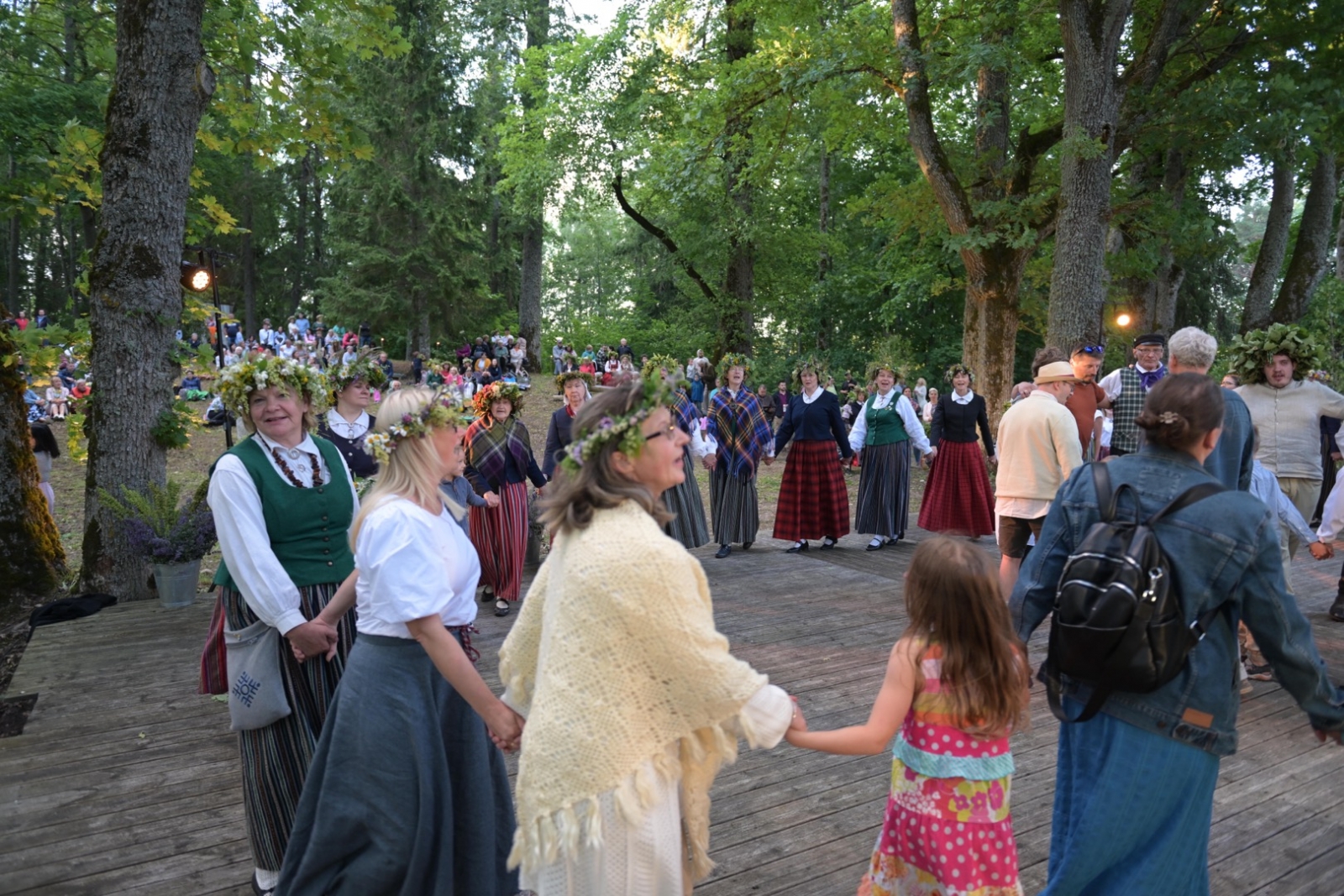 Cilvēki iet aplī-rotaļā Plāteres pilskalnā 20.06.2024.