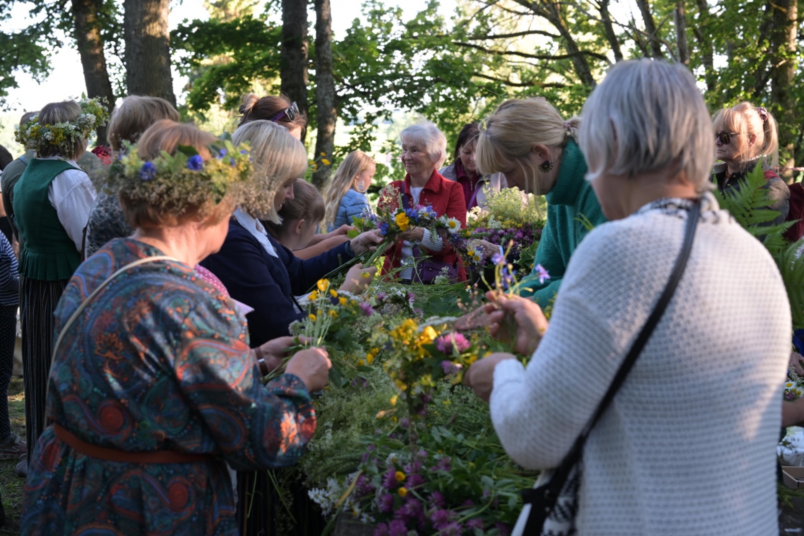 Cilvēki pin Jāņu vainagus Plāteres pilskalnā 20.06.2024.
