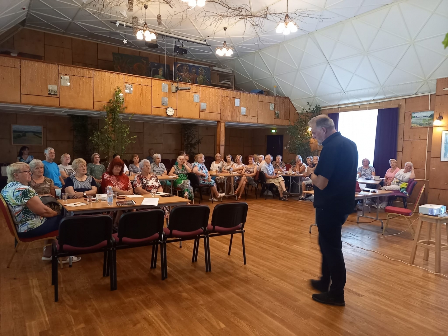 Seniori Tautas nama zālē klausās Egila Stūrmaņa lekciju