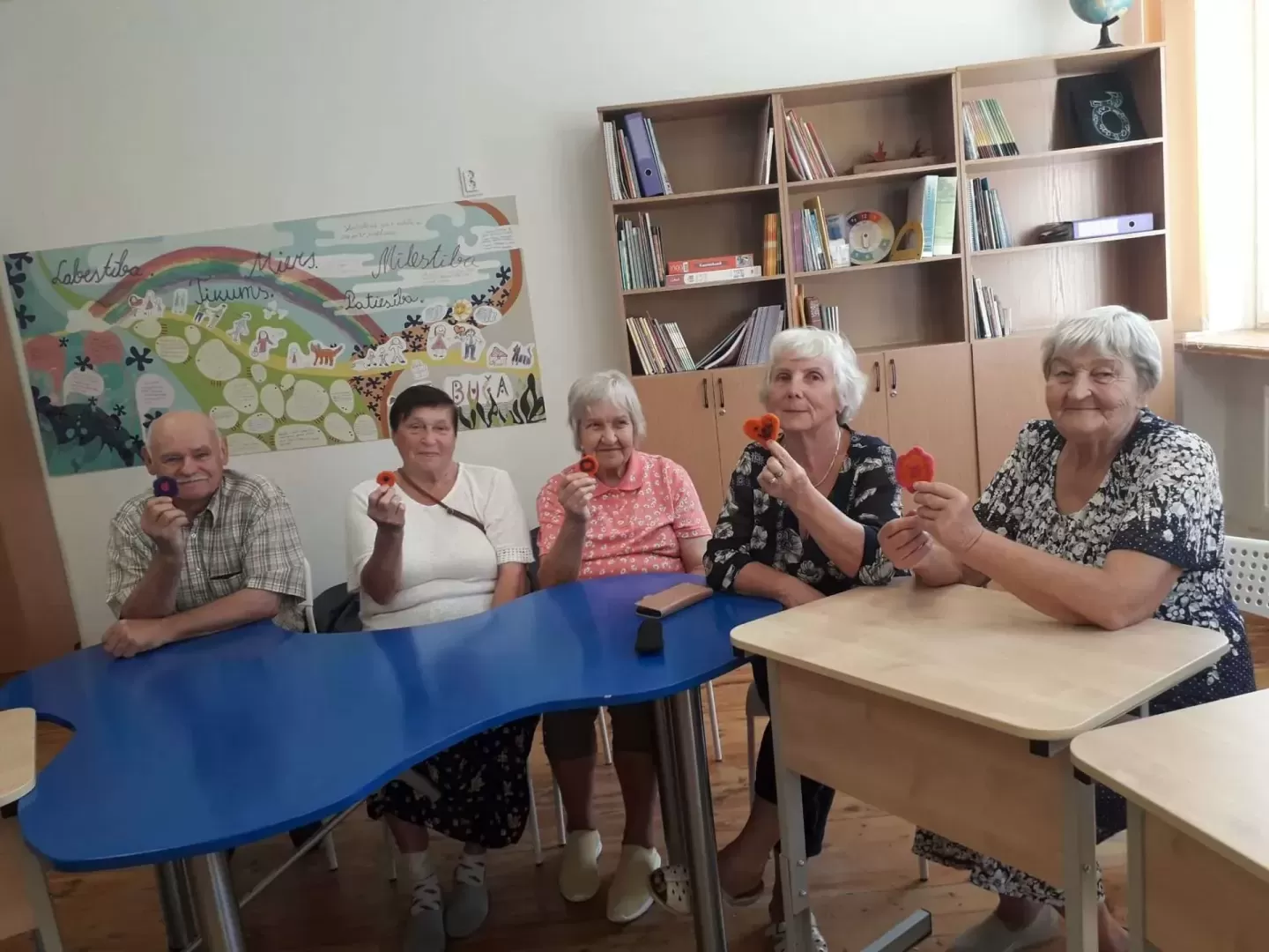 5 seniori sēž pie galda ar filca sirsniņām rokās 08.2024.