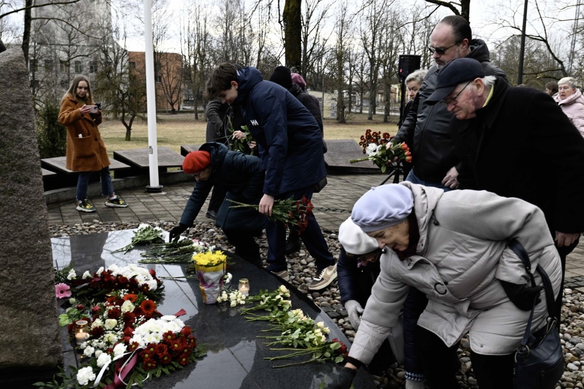 Cilvēki noliek ziedus pie politiski represēto piemiņas akmens Ogrē