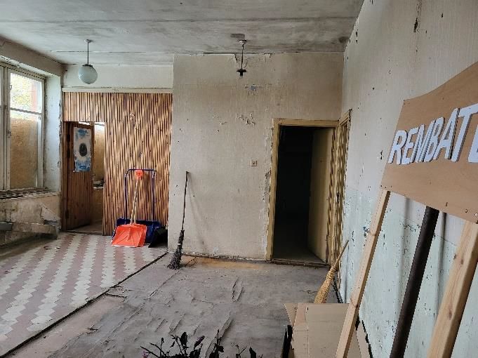 Sakaru nodaļa Rembate-iekštelpas bēšas sienas, nolupis apmetums, durvis un logs