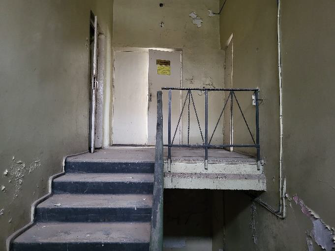 Sakaru nodaļa Rembate-iekštelpas bēšas sienas, nolupis apmetums, kāpnes, durvis