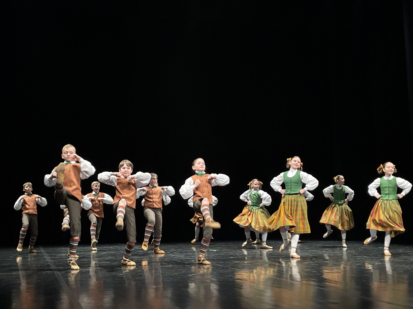Skolēnu tautas deju skates dalībnieki uz skatuves tautas tērpos