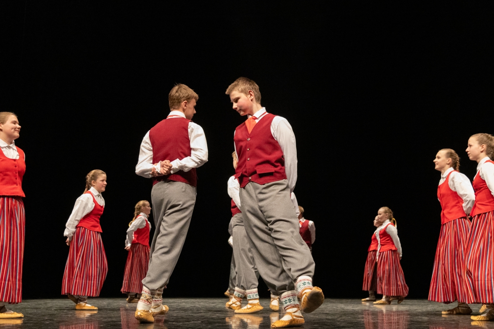 Skolēnu tautas deju skates dalībnieki uz skatuves tautas tērpos
