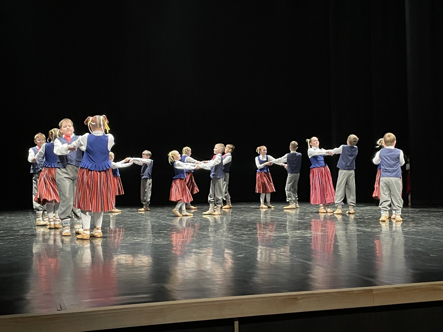 Skolēnu tautas deju skates dalībnieki uz skatuves tautas tērpos