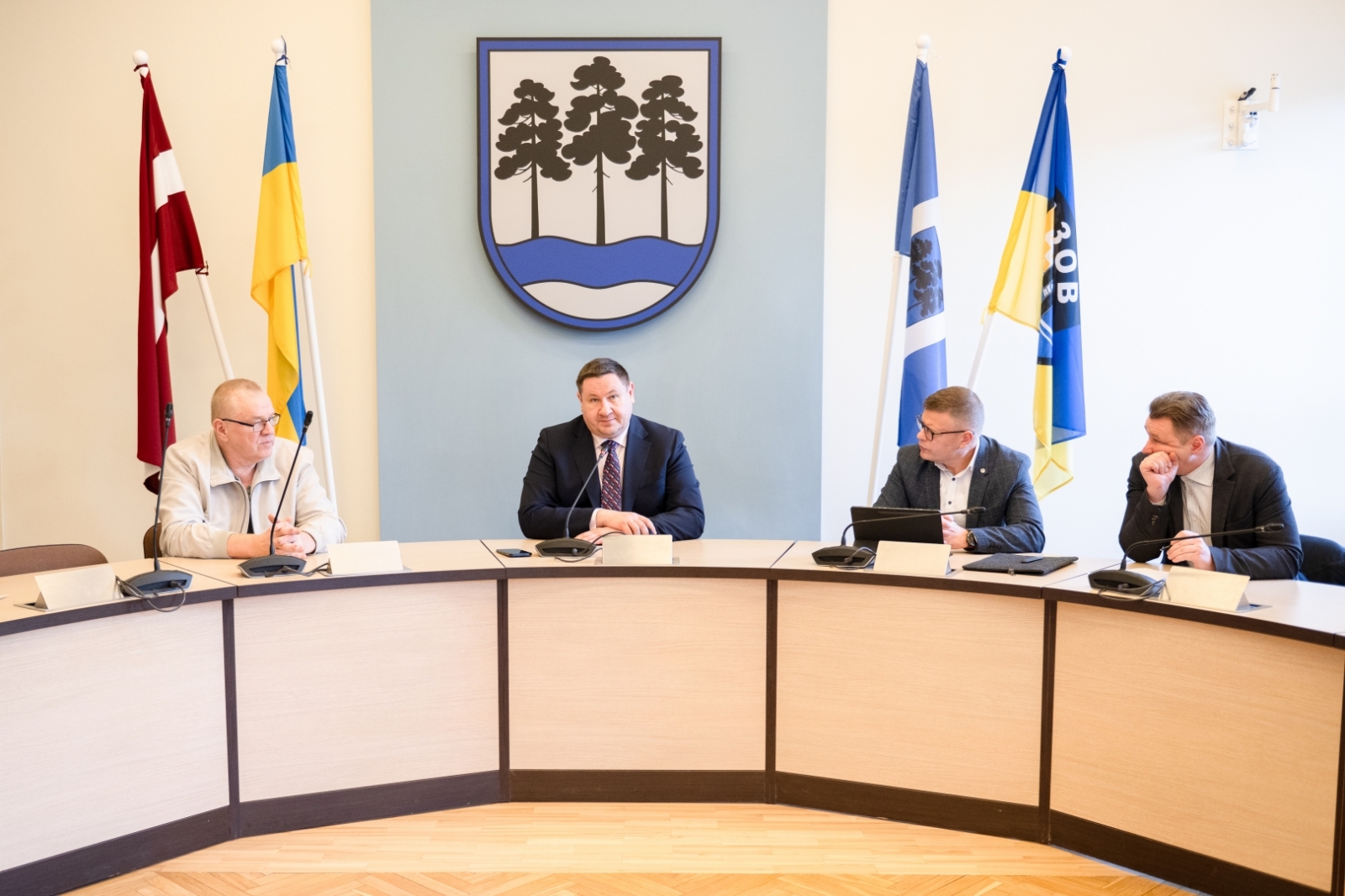 Egils Helmanis, Indulis Trapiņš un Latvijas Valsts ceļu pārstāvji sēž pie galda domes sēžu zālē