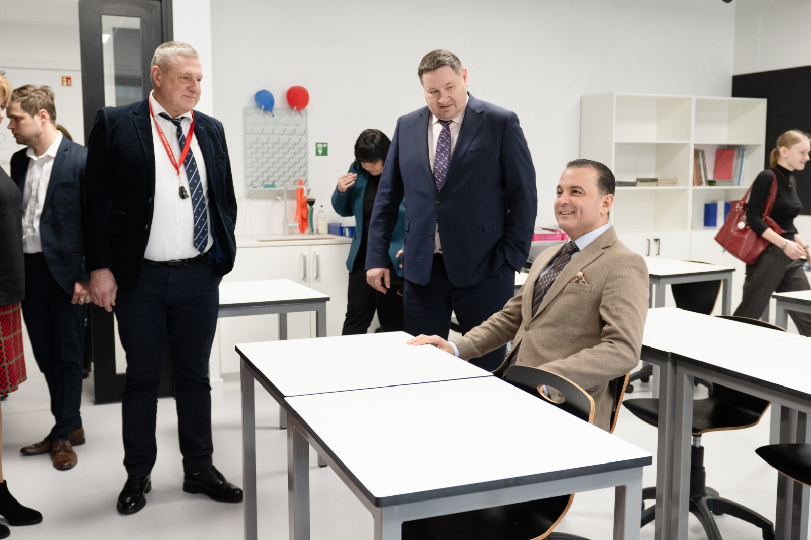 Ministrs sēž skolas solā, blakus stāv Egils Helmanis un Dainis Širovs