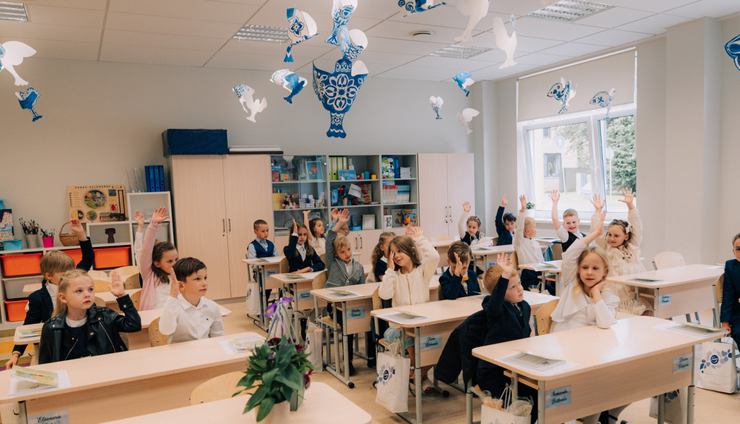 1. septembris Ogres novada skolās. Attēlā 1. klases skolnieki sēž solos ar paceltām rokām