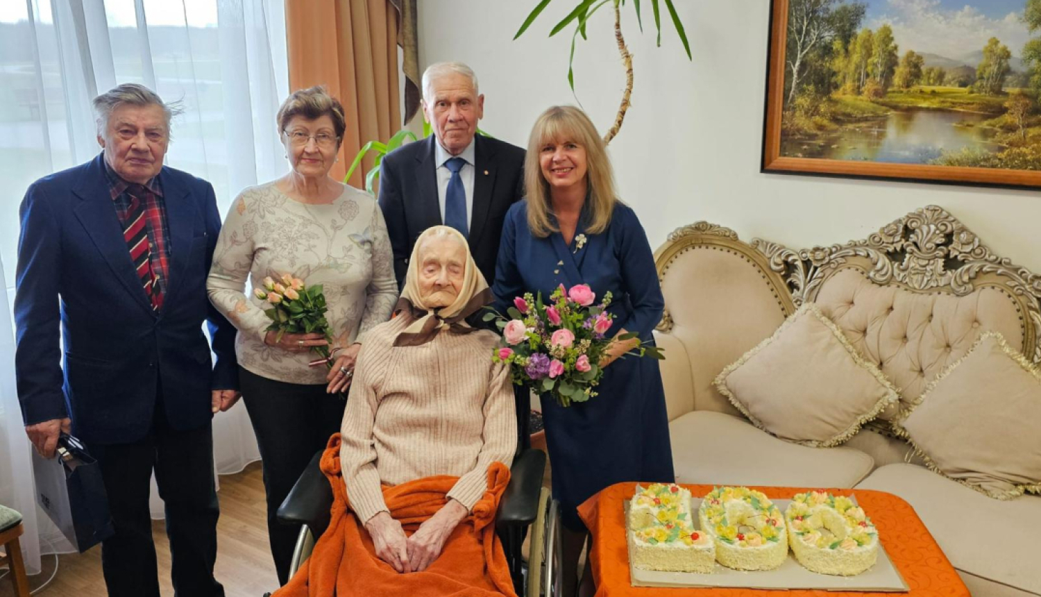 Deputāte Sarmīte Ozoliņa un Ogres politiski represēto kluba biedri kopā ar jubilāri Malvīni Asari, līdzās - torte, kas veidota formā "100"
