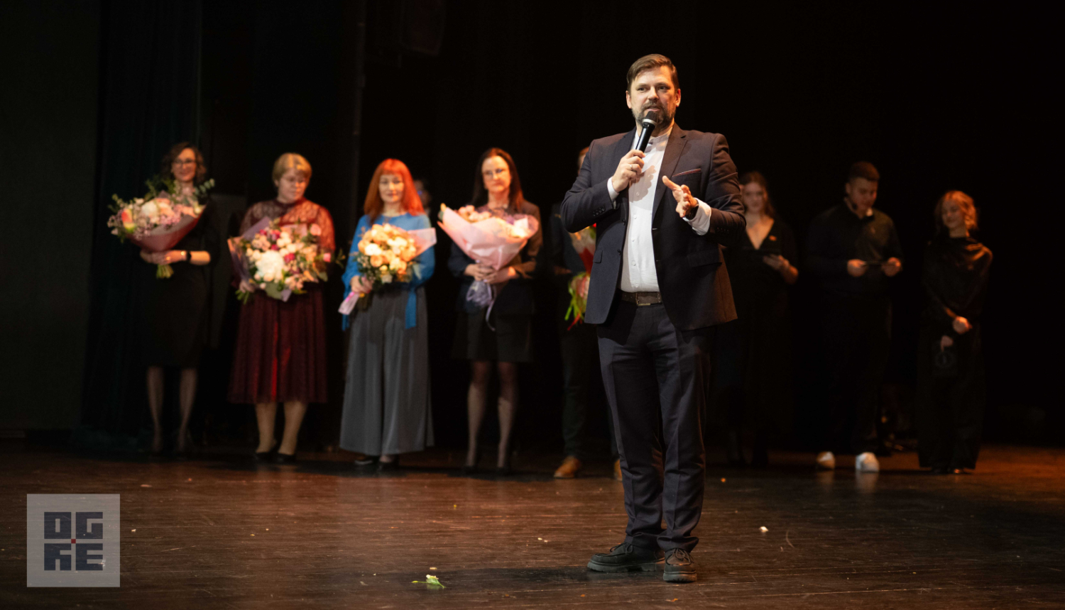 Ogres novada pašvaldības domes priekšsēdētājs Andris Krauja saka uzrunu 2026. gada Ogres Valsts ģimnāzijas žetonvakarā. Aiz viņa - ģimnāzijas skolotāji