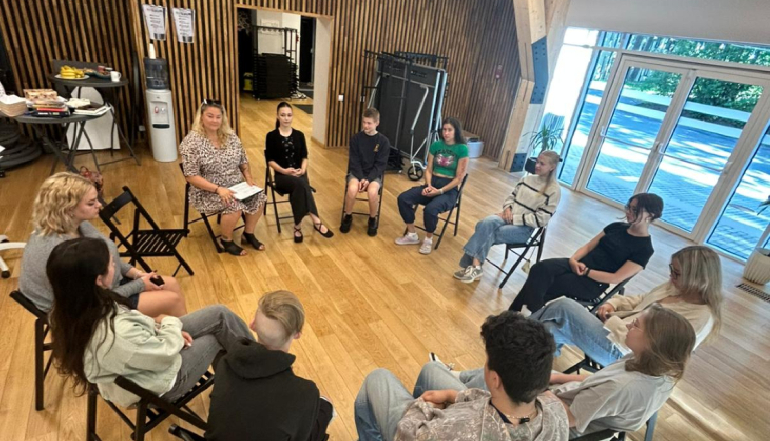 Dienas nodarbības Ogres Jauniešu mājā par brīvprātīgo darbu – jaunieši atklāj motivāciju, līderību un pārliecību par saviem spēkiem. Attēlā jaunieši sēž aplī un apgūst jaunās zināšanas