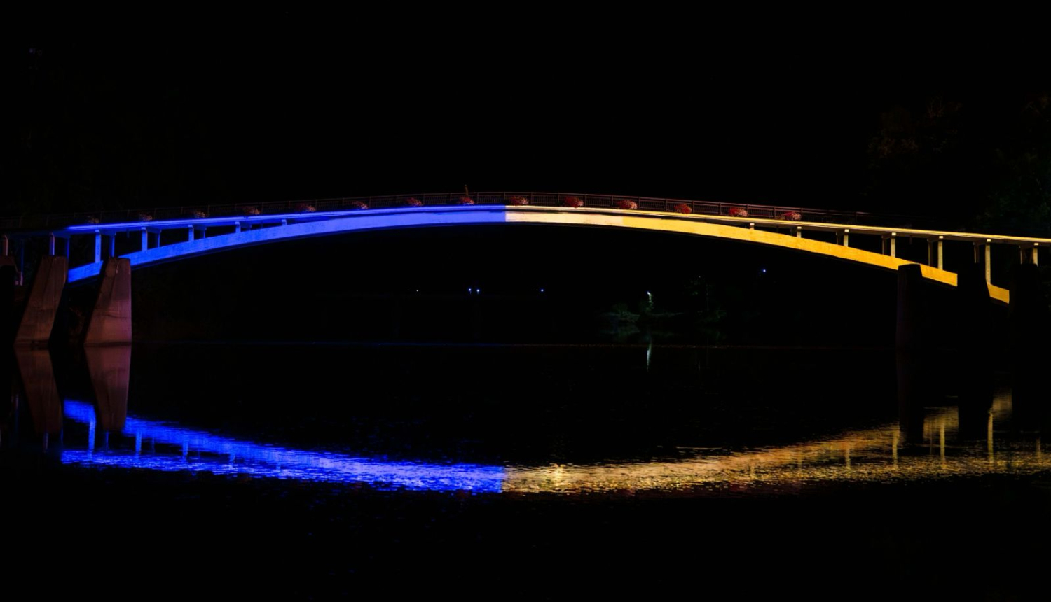 Ukrainas karoga krāsās izgaismotais gājēju tilts pār Ogres upi
