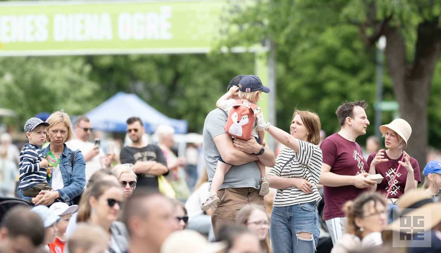 7. jūnijā Ogrē norisinājās tradicionālās ĢIMENES DIENAS svinības, kurās ar vērienīgu pasākumu programmu apmeklētāji varēja sajust kopā būšanas prieku un piedalīties kopīgās aktivitātēs visai ģimenei. Attēlā ģimenes ar bērniem, fonā baneris ar uzrakstu - Ģimenes diena Ogrē
