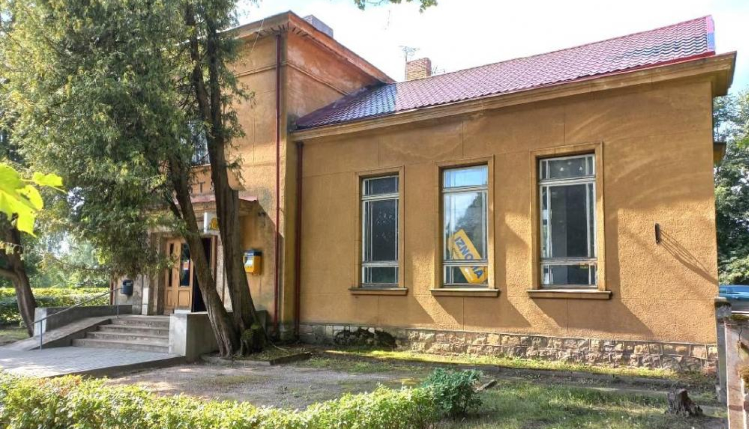 VAS "Latvijas Pasts" ēka ar koku un krūmu stādījumiem priekšplānā