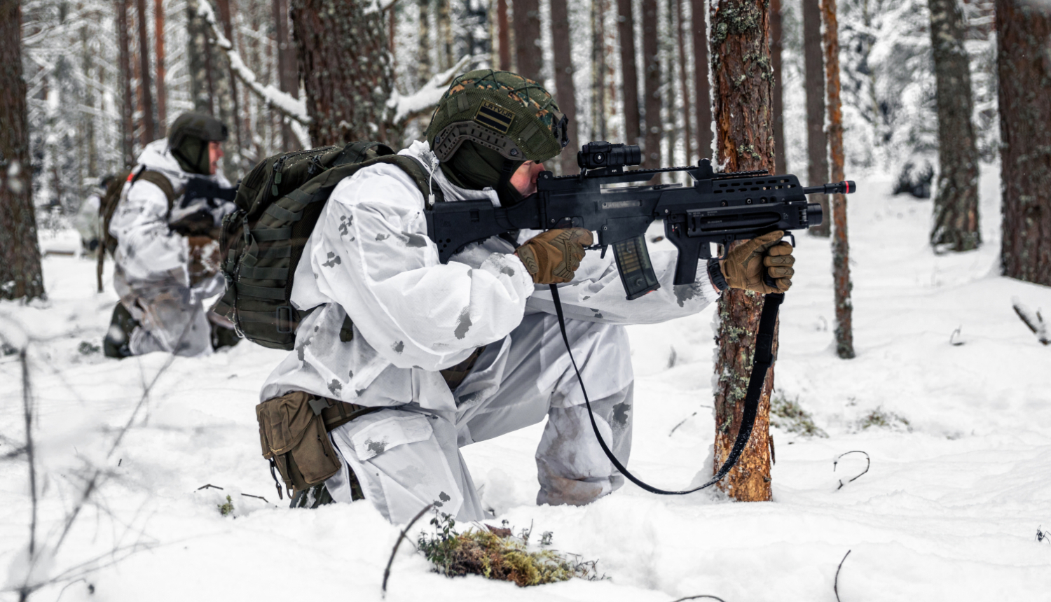 Divi karavīri baltos aizsargtērpos ar ieročiem mācību laikā mežā ziemas apstākļos