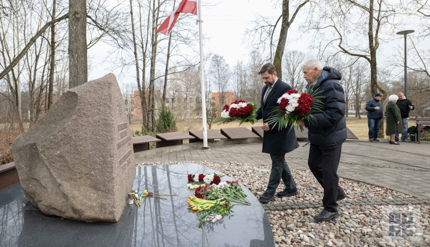 Ogres novada pašvaldības domes priekšsēdētājs Andris Krauja un Ogres Politiski represēto kluba vadītājs Ivars Kaļķis 2026. gada 25. martā noliek ziedus pie piemiņas akmens Ogrē