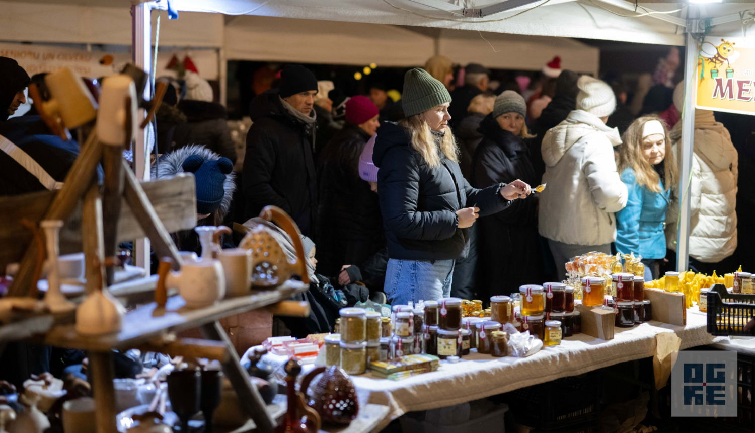 Gadatirgus apmeklētāji aplūķo priekšplānā izvietotos stendus ar māla izstrādājumiem un biškopības produktiem