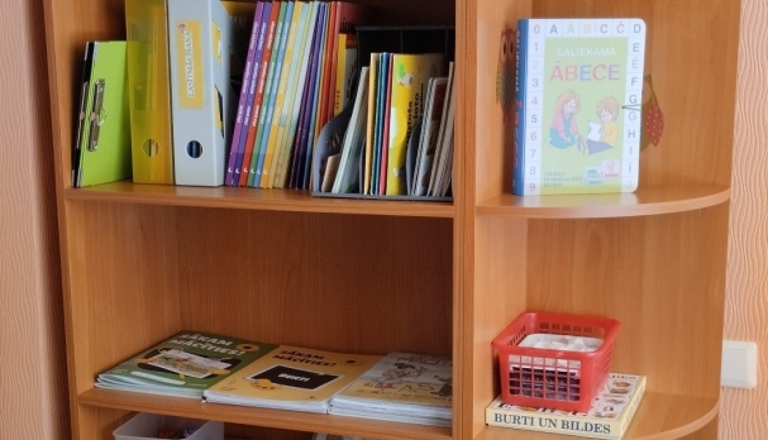 Grāmatu plaukts ar informatīvajiem materiāliem vecākiem, kuri neizvēlas bērnu izglītot pirmsskolas izglītības iestādē