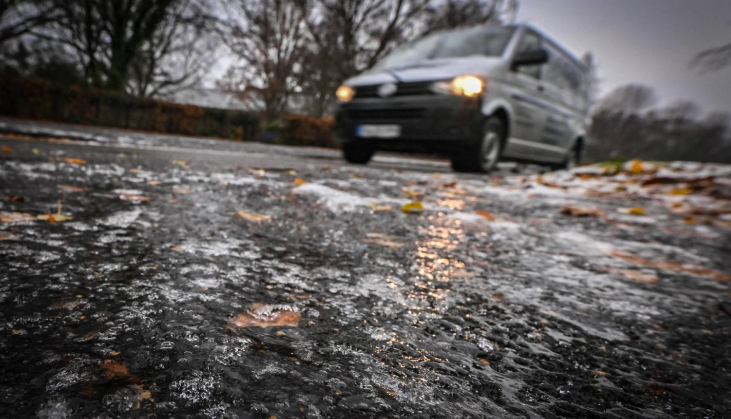 Apledojis ceļš rudenī, automašīna, ledū iesalušas krāsainas rudens lapas