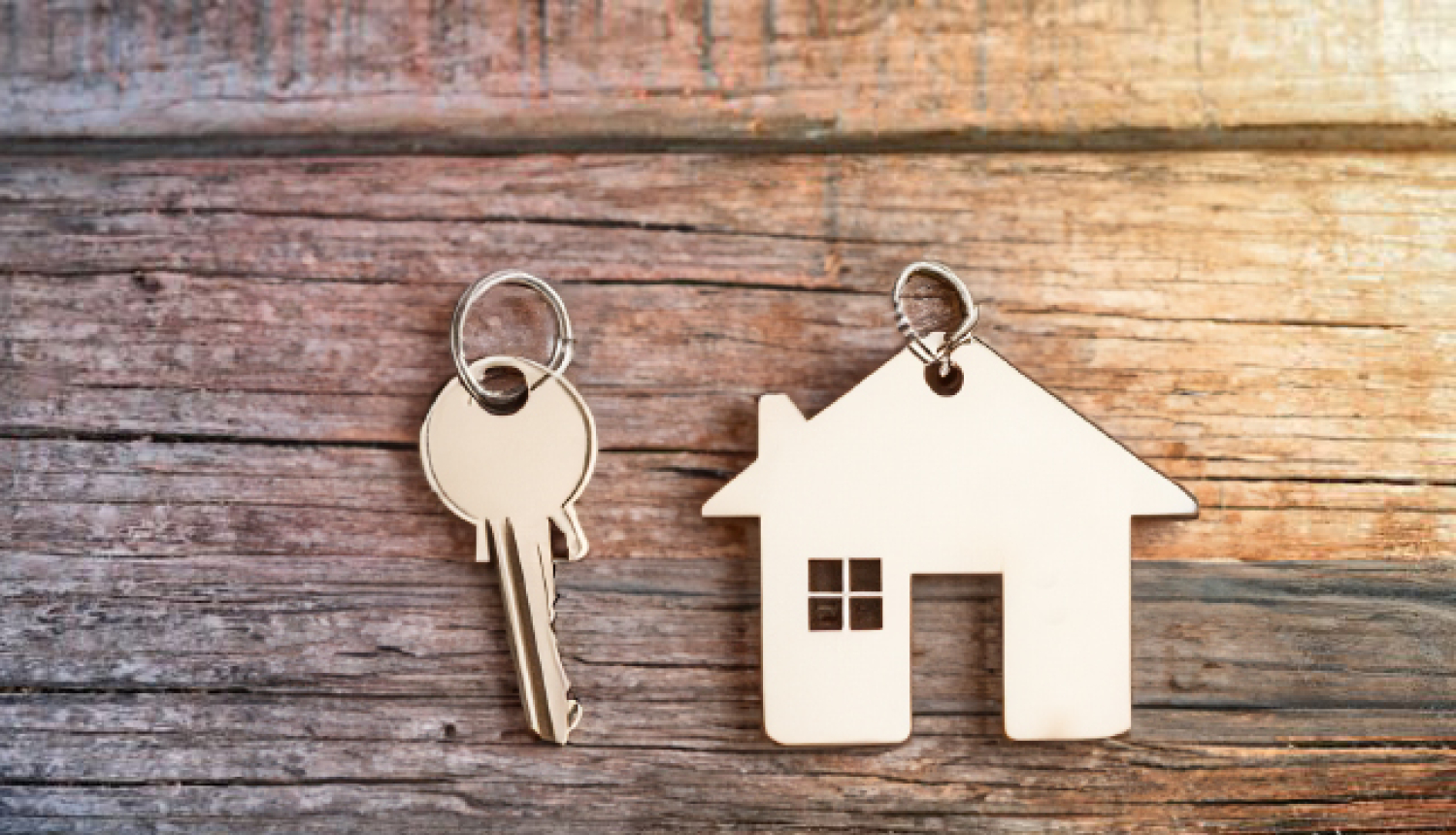 Atslēga un breloks mājas izskatā uz koka fona