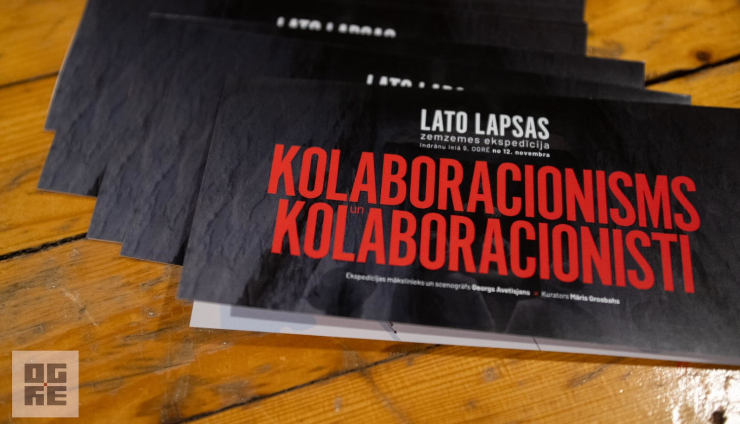 Izstādes bukleti - uz melna fona sarkans teksts: "Lato Lapsas zemzemes ekspedīcija “Kolaboracionisms un kolaboracionisti” Indrānu ielā 9, Ogrē, no 12. novembra