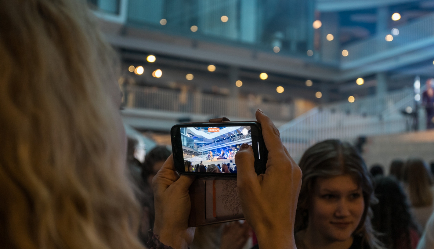 Meitene ar mobilo telefonu filmē koncertu