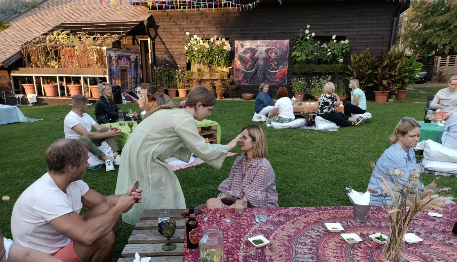 Cilvēki sēž pie galdiem, tiek krāsotas sejas 