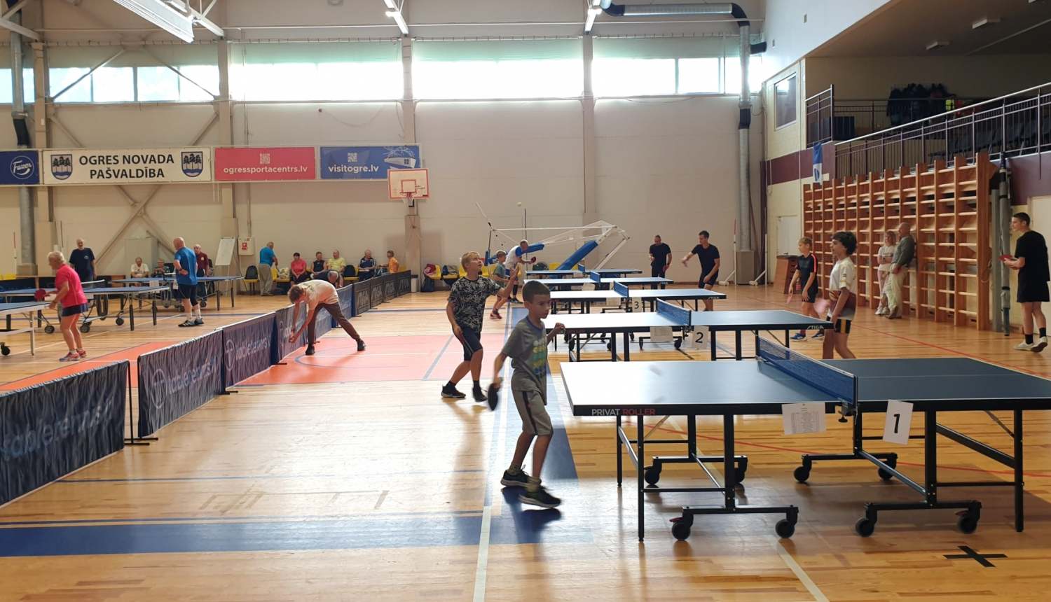 Bērni pie vairākiem galdiem spēlē galda tenisu 28.09.2024.