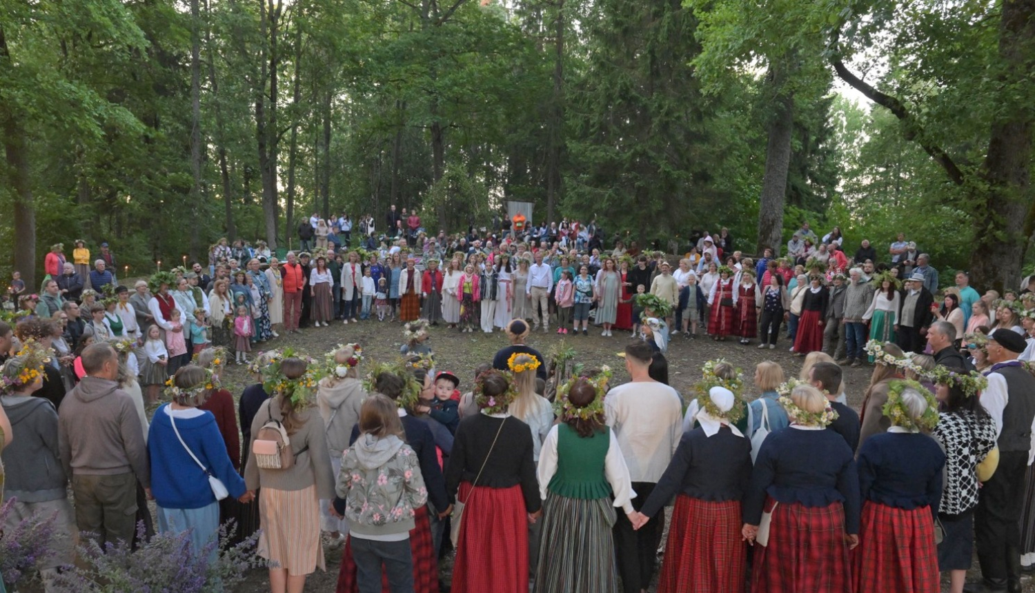 Cilvēki stāv aplī Plāteres pilskalnā 20.06.2024.