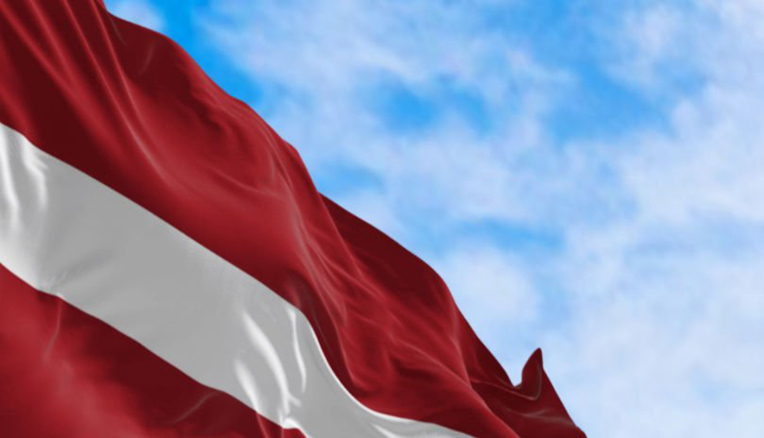 Latvijas Valsts karogs uz zilu debesu fona