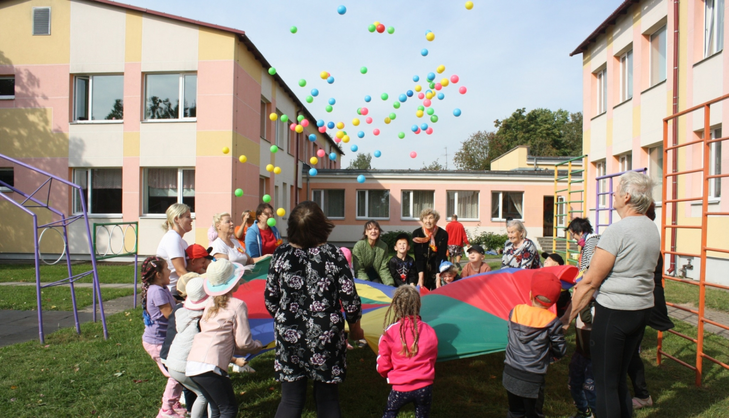 Bērni ar senioriem uz liela auduma met bumbas 09.2024.